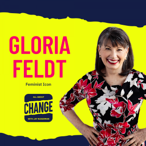 Square graphic with blue and yellow background. The blue is on the top and bottom and the yellow is sandwiched in between. On the right side is a photo of Gloria Feldt. She has black and gray hair. She is wearing pearl earrings, has red lipstick on, and is smiling. She is wearing a red, black, and white flower dress. She has her hands on her hips. On the top in red bold letters reads “Gloria Feldt”. Below in blue reads “Feminist Icon.” Below is an All About Change logo. It's blue on top and bottom with yellow sandwiched in the middle. Top blue with yellow text reads "All About", Middle Yellow with blue text reads "Change", and bottom blue with yellow text reads "With Jay Ruderman."